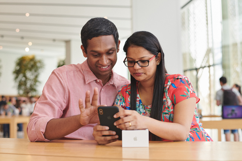 Male and female customer try out the iPhone Xs Max.