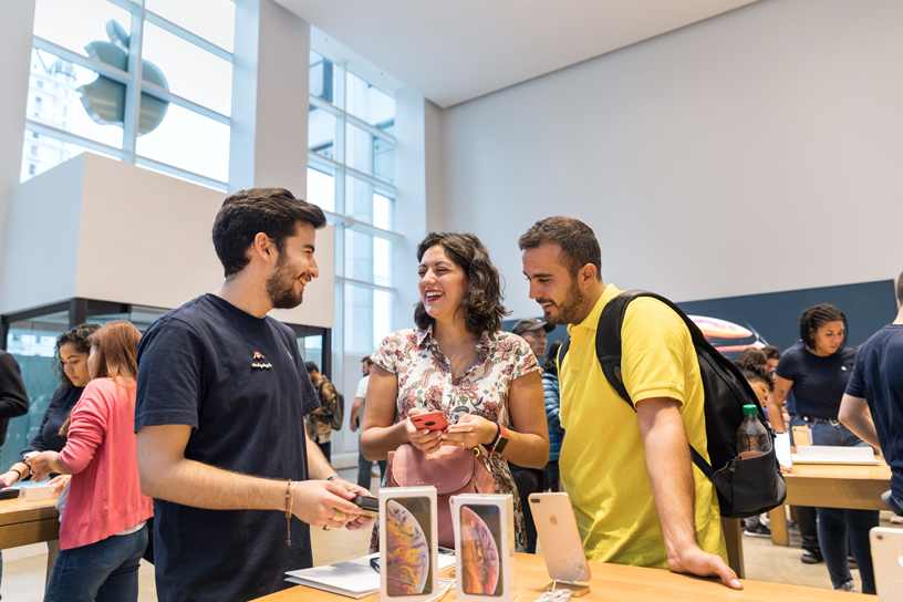 An Apple team member talks with two customers checking out iPhone Xs Max.