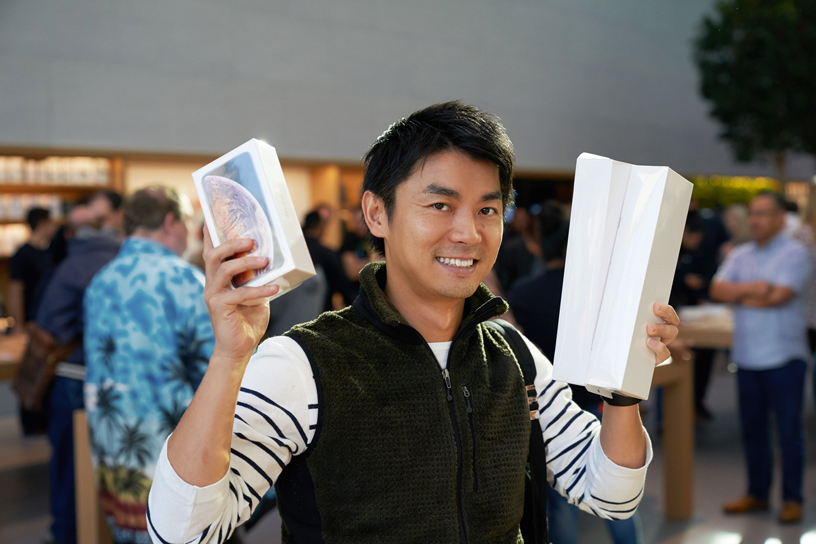 A man holds up boxes for the iPhone Xs and Apple Watch Series 4.