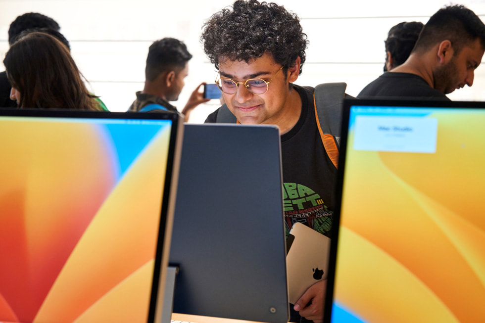 A customer stands at a table and tests out iMac.