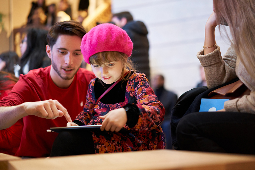 Apple team member showing a little girl how to use iPad.
