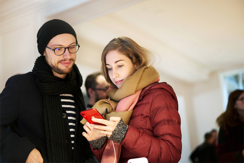 Two customers using the red iPhone XR. 