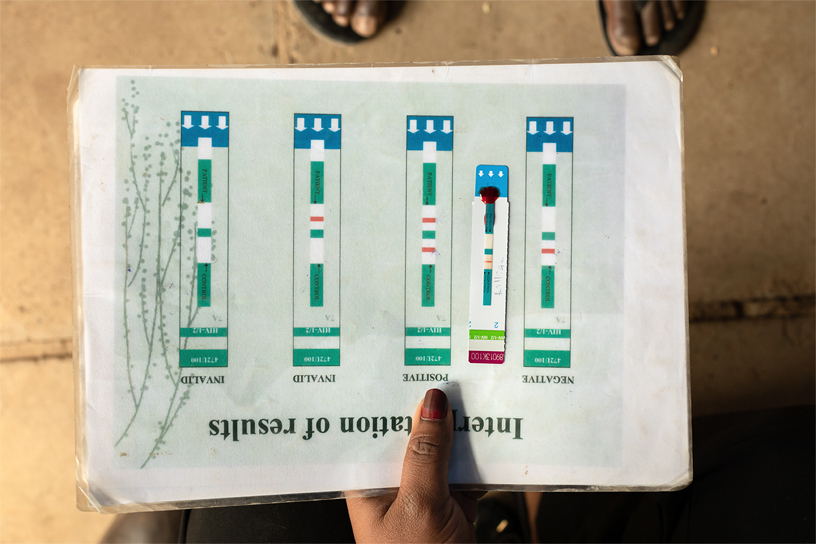 A test strip in between examples of positive and negative results.