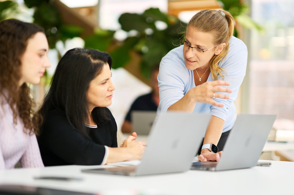 Stephanie Worladge mentoring two students on MacBook devices.