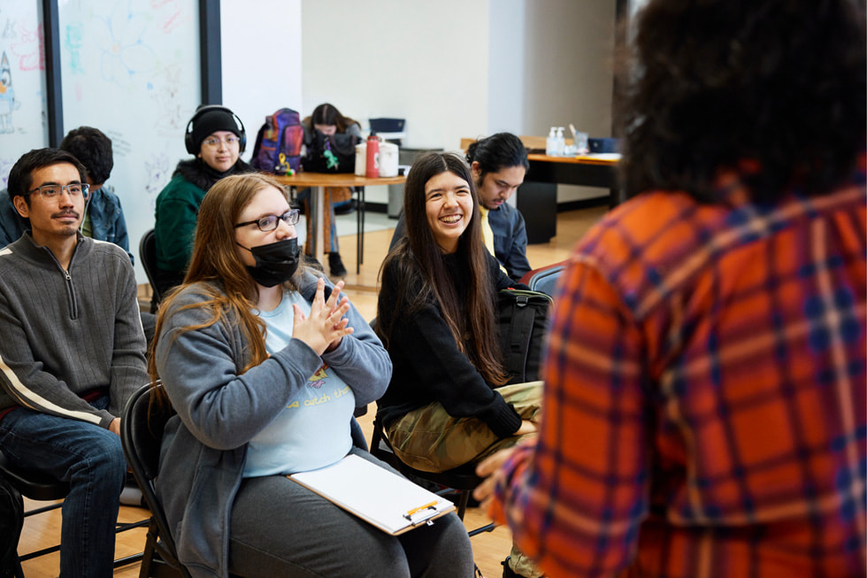 Instructor Jessica “Jess” Jerome is shown from behind, speaking with students in a classroom setting. 