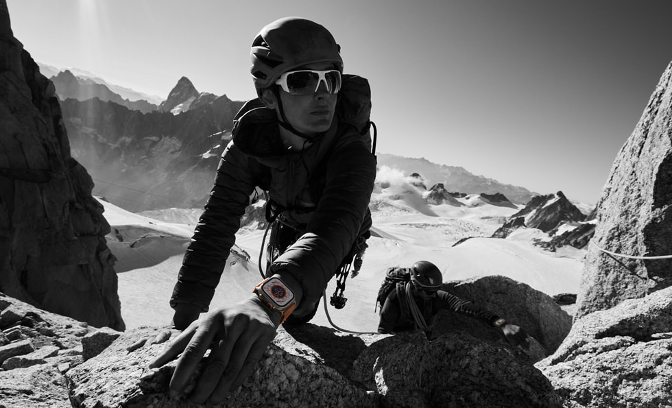 A person uses Apple Watch Ultra while climbing rocks in a mountainous setting.