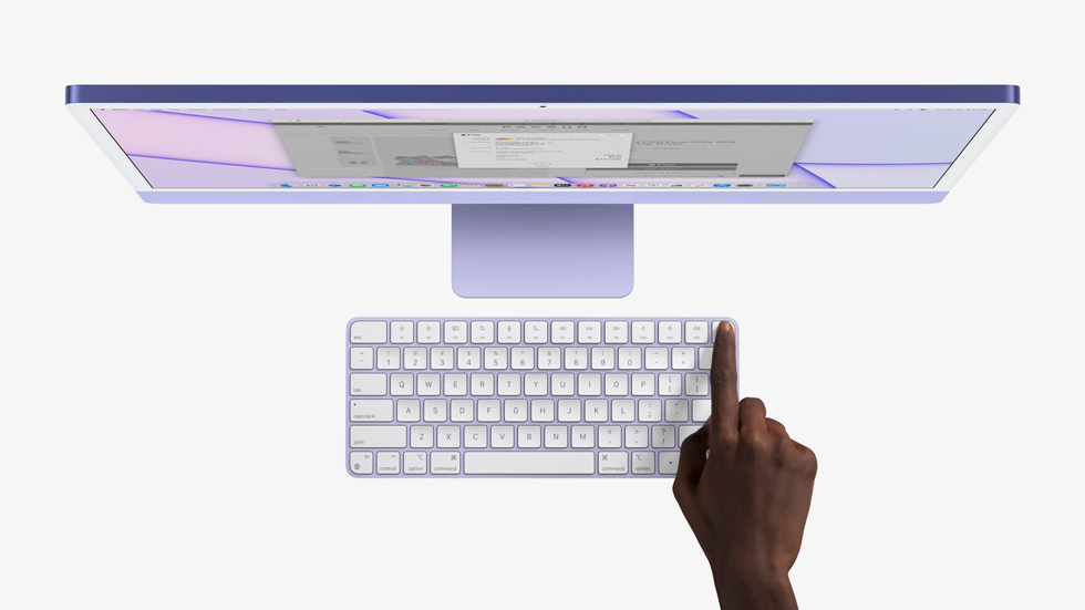 A finger presses Touch ID on Magic Keyboard to turn on iMac.