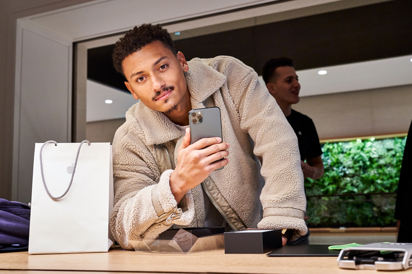 Customer holding iPhone 11 Pro Max at Apple Champs-Élysées.