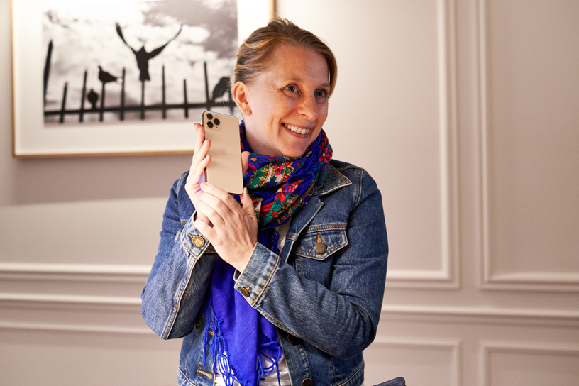A customer holding up iPhone 11 Pro at Apple Champs-Élysées.