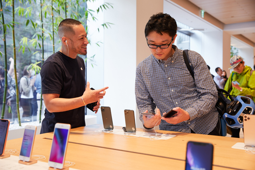 An Apple team member talks to a customer checking out iPhone 11 Pro at Apple Marunouchi.