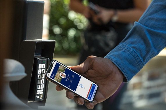 A student badging into a campus building using his contactless student ID card on an iPhone.