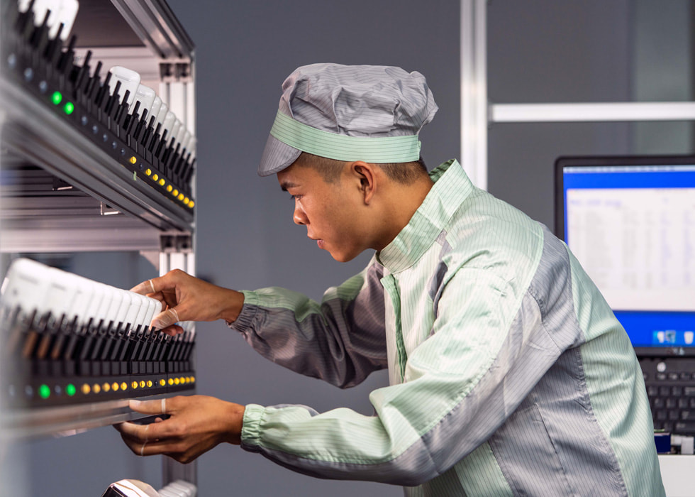 A man in protective clothing examines equipment in a lab setting.
