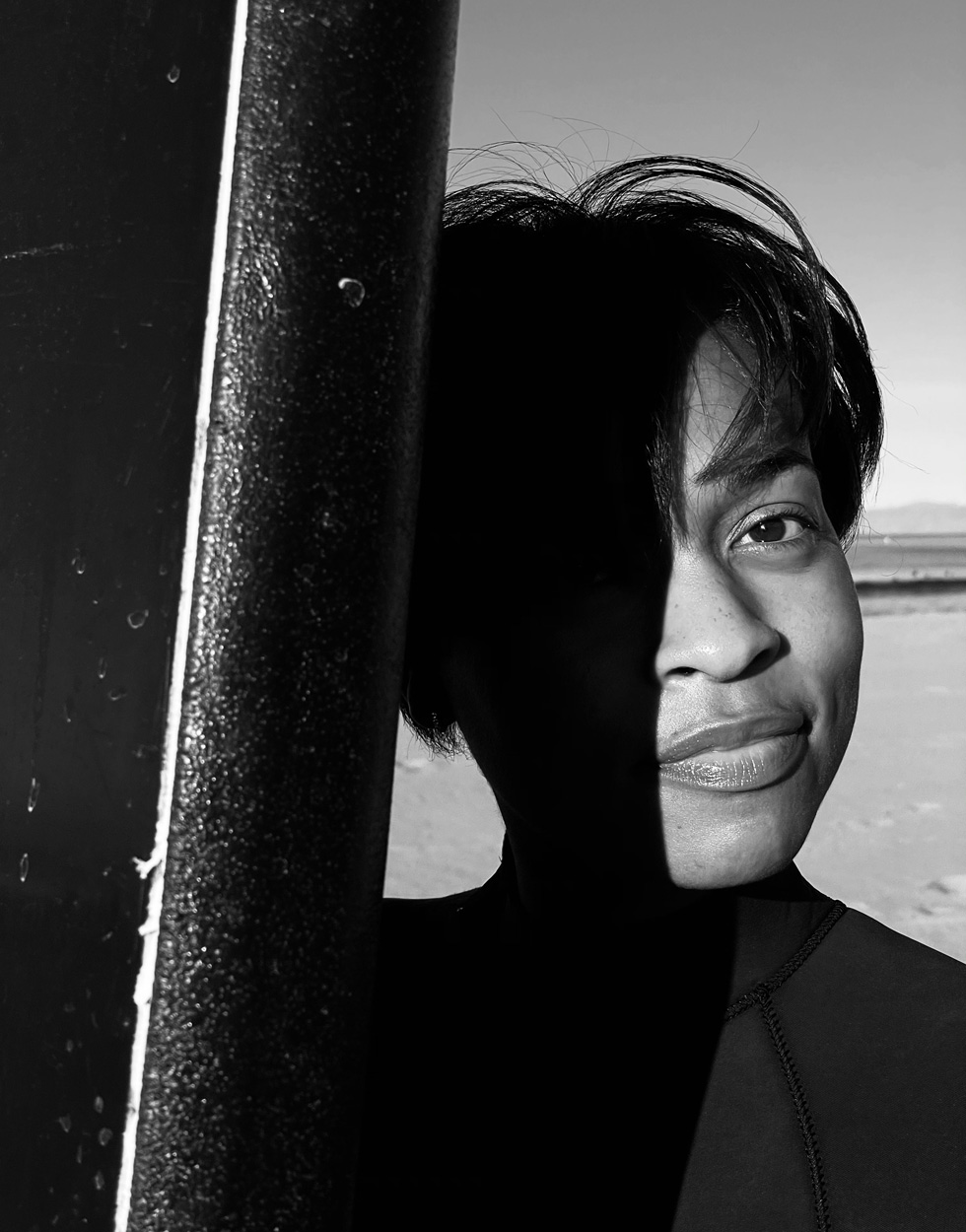 Ludine with surfboard, on the beach.