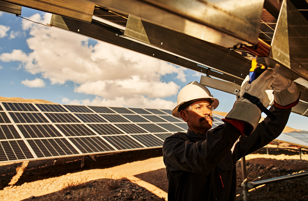A technician works on a solar panel outdoors.