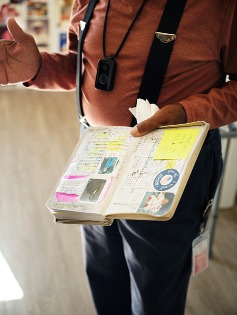 Veterans Square housing complex resident J.C. holds his open planner, which is covered in stickers and photos.