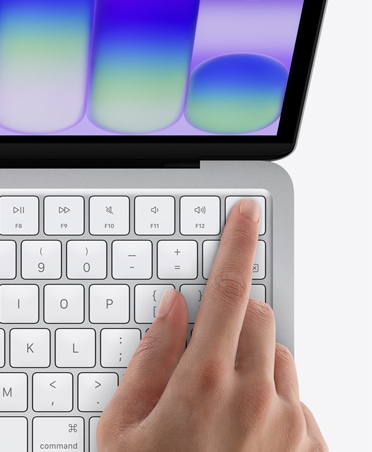 MacBook Neo, culoarea Argintiu, degetul unei persoane pe senzorul Touch ID în colțul din dreapta-sus al tastaturii