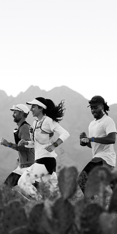 Traja ľudia pri behu v púšti sledujú svoj tréning na Apple Watch Ultra 3