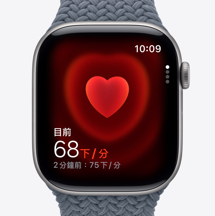 Apple Watch Series 11，展示太空灰色鋁金屬錶殼，搭配錨藍色編織單圈錶環，螢幕顯示心率 app 的每分鐘心跳數畫面