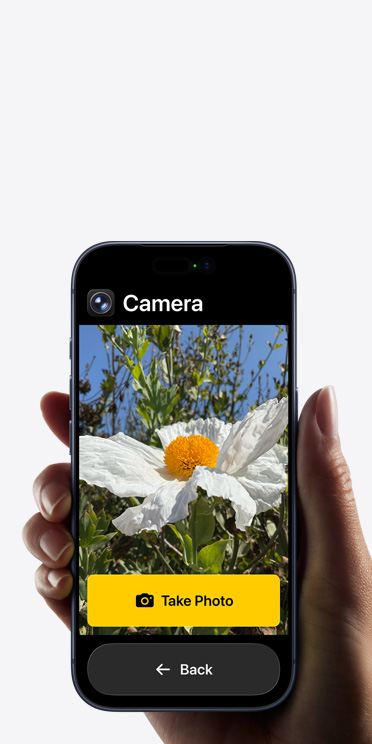 Écran d’iPhone 17 Pro affichant l’interface simplifiée de l’app Appareil photo avec une fleur blanche dans le cadre, le bouton « Prendre une photo » et le bouton « Retour » en dessous