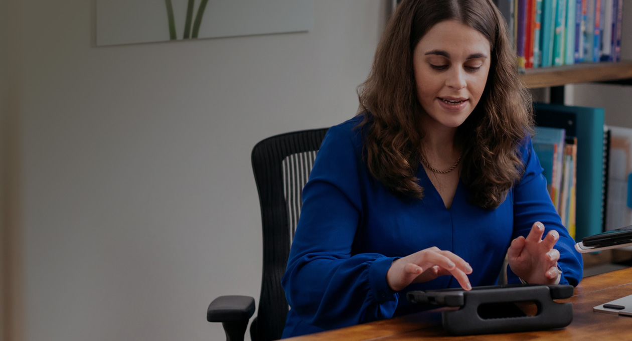 Photo of Apple Distinguished Educator and disability advocate Jordyn Zimmerman sitting at desk and typing on an iPad screen