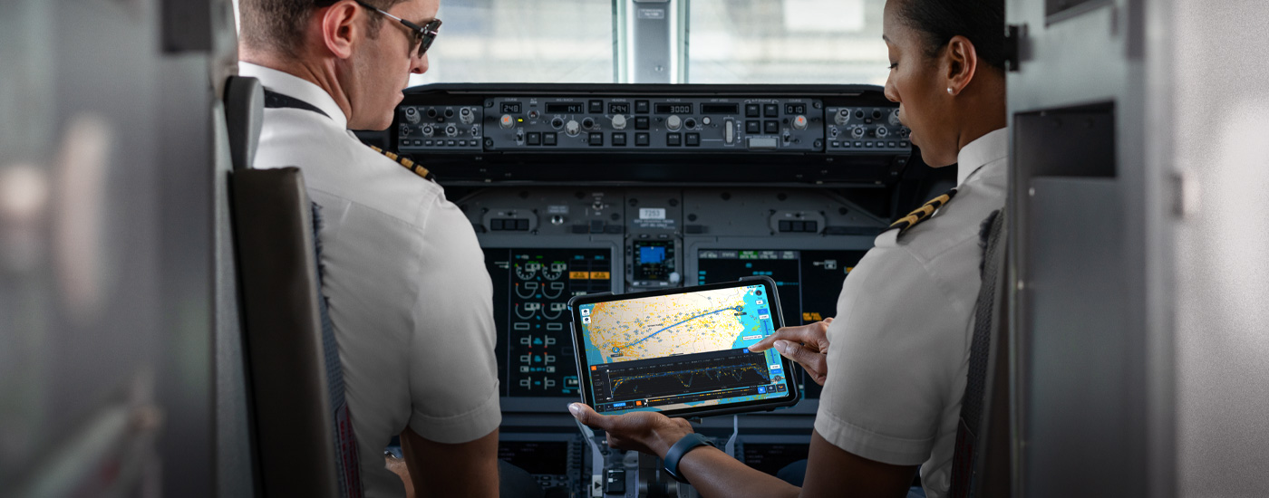 Two pilots in a cockpit looking at an iPad with a map on it.