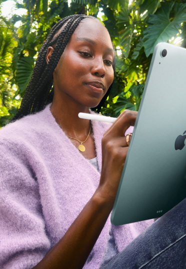 A student sitting outdoors. She’s holding an iPad and an Apple Pencil Pro.