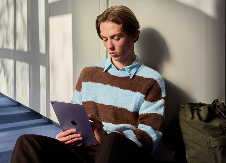 Una persona seduta sul pavimento in una stanza piena di luce, che usa iPad e Apple Pencil.