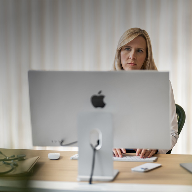 Une prestataire assise à son bureau derrière un écran d’iMac.
