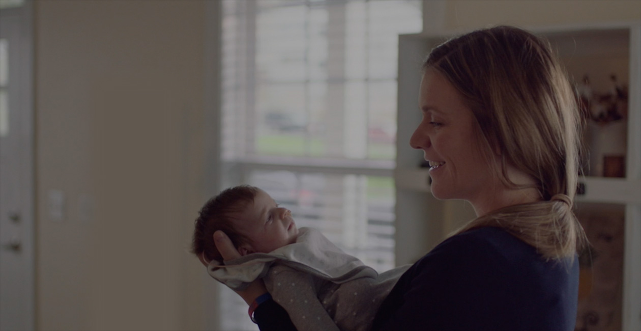 Una madre sonríe junto a su bebé recién nacido.