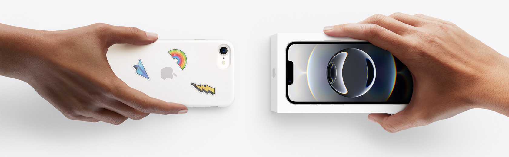 Dos manos se intercambian un iPhone antiguo y un iPhone 16e nuevo en su caja.