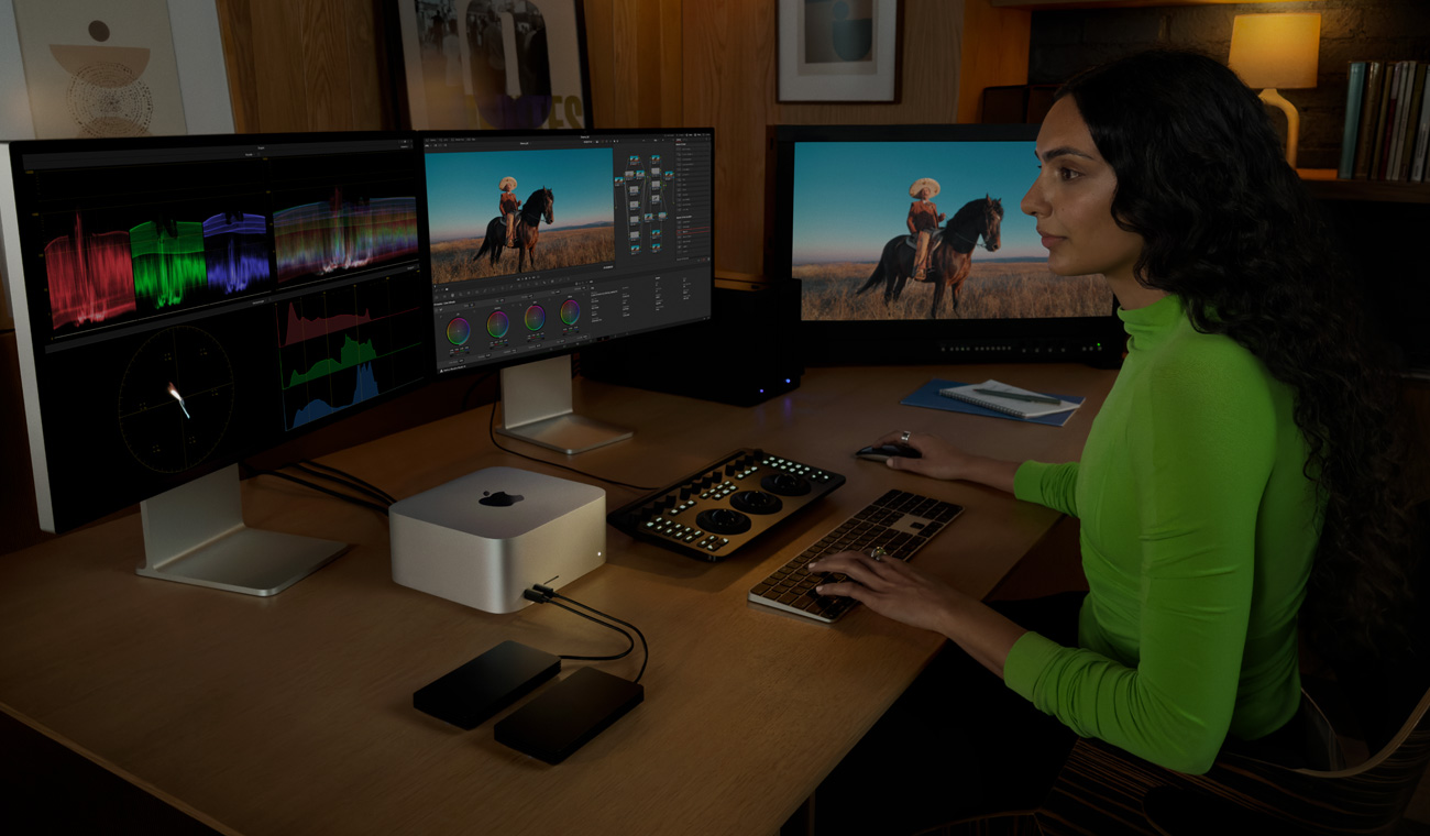 Profesionál míchá hudbu v DaVinci Resolve Studiu na Macu Studio se třemi připojenými displeji